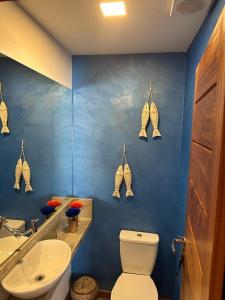 a blue bathroom with a toilet and a sink at Condominio Viva Barra in Barra Grande