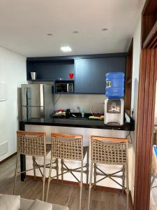 a kitchen with a counter with three chairs and a counter top at Condominio Viva Barra in Barra Grande