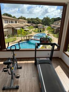 einen Fitnessraum mit Blick auf den Pool durch ein Fenster in der Unterkunft Condominio Viva Barra in Barra Grande