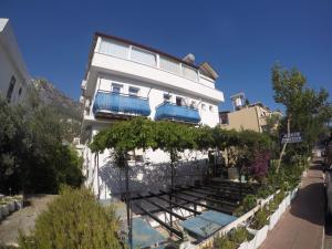 a white building with blue balconies on a street at Akkin Pansiyon in Kaş