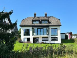 una casa blanca con ventanas negras en un campo verde en Romantikchalet Neuastenberg/Winterberg, en Winterberg