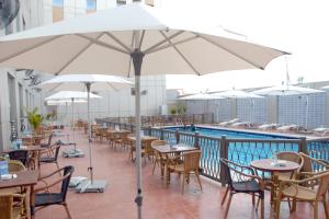 a patio with tables and chairs and umbrellas next to a pool at Ibis Yanbu in Yanbu