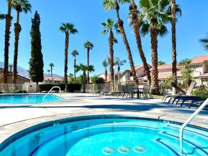 a swimming pool with palm trees in a resort at Two Chic at Mountain Shadows in Palm Springs
