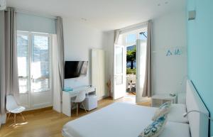 a white bedroom with a bed and a tv at Ca del Lac Rooms in Castro