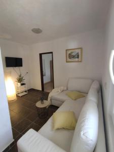 ein Wohnzimmer mit einem weißen Sofa und einem TV in der Unterkunft Apartmani Paraiso in Sevid