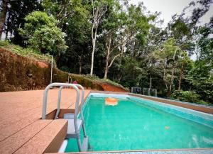 a swimming pool with a bench next to at 900 Woods Wayanad Eco Resort - 300 Acre Forest Property Near Glass Bridge in Meppādi