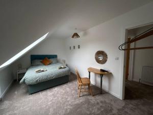 1 dormitorio con 1 cama y 1 mesa con silla en 3 - Rabbit Warren, Bright décor home & private hot tub, en Norwich