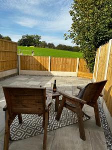 a patio with a bench and a table and a bottle of wine at Ivy Cottage Derbyshire in South Wingfield
