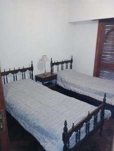 2 Einzelbetten in einem Schlafzimmer mit einer Lampe auf einem Tisch in der Unterkunft Cómo en casa in Rosario