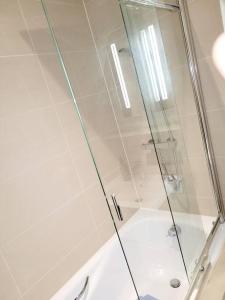 um chuveiro com uma porta de vidro na casa de banho em 2 BEDROOM APT WITH 2 COMFORTABLE KING SIZE BEDs, FREE PRIVATE PARKING, EASY ACCESS TO LONDON em West Byfleet