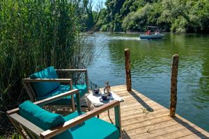 a wooden dock with two chairs and a boat on a lake at Wineport Lodge Agva in Ağva