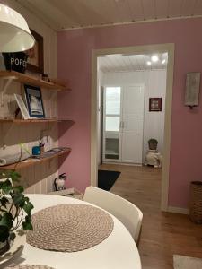 a living room with a table and a pink wall at Lilla gröna huset på gården in Härnösand