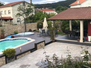 un patio trasero con piscina y cenador en A casa da charca en Puentecesures