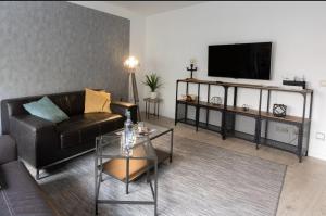a living room with a black leather couch and a flat screen tv at Ottostadt in Magdeburg