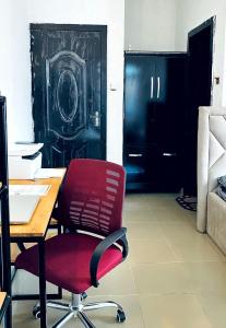 an office with a red chair and a desk and a door at Cozy Apartment in the City Centre - Rayfield Jos in Zawan