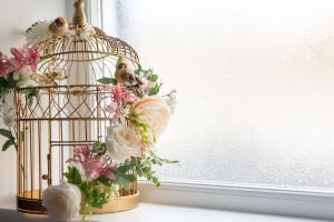 a bird cage with flowers on a window sill at Beaumont House in Royal Tunbridge Wells