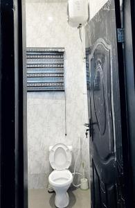 a bathroom with a toilet and a black door at Cozy Apartment in the City Centre - Rayfield Jos in Zawan