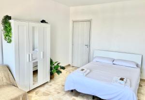 a white bedroom with a bed and a chair at Skyscraper 11 in Cinisello Balsamo