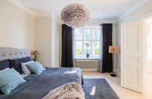 1 dormitorio con cama azul y ventana grande en Lägenhet i sekelskifteshus centrala Kalmar, en Kalmar