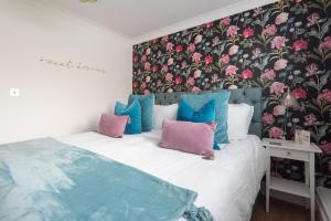 a bedroom with a bed with pink and blue pillows at Beaumont House in Royal Tunbridge Wells
