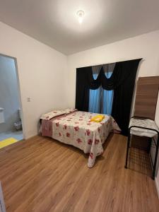 a small bedroom with a bed and a chair at Suíte Hostel Curitiba in Curitiba
