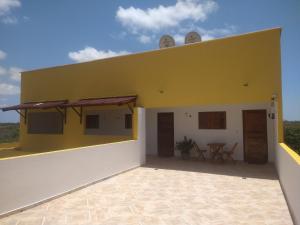 a yellow and white building with a table on it at Pousada Mar de Miroca in São Miguel do Gostoso