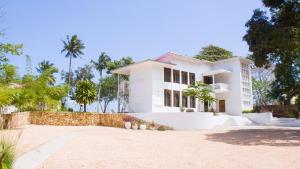 a white house with palm trees in the background at The Cliff 2 Bedroom Beach Apartment in Mazizini