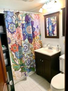 a bathroom with a flower shower curtain and a sink at Cozy First Floor Apartment in Chicopee