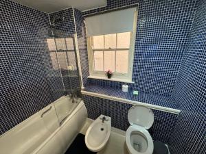a blue tiled bathroom with a toilet and a sink at A stunning apartment in Paddington in London