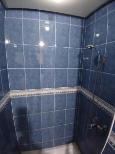a blue tiled shower with a glass door at Appartement Casa Voyageurs in Casablanca