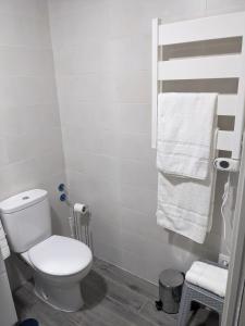 La salle de bains est pourvue de toilettes blanches et d'une serviette. dans l'établissement Apartamento Rural Zahora, à Hervás