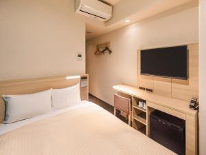 a hotel room with a bed and a desk with a tv at Sotetsu Fresa Inn Osaka Namba in Osaka