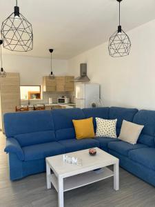 ein blaues Sofa im Wohnzimmer mit einem Tisch in der Unterkunft CASA LOS ABUELOS in Puerto del Rosario