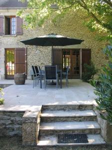 a patio with a table and an umbrella at Charme en Champagne in Trémilly
