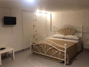 - une chambre avec un lit et une télévision murale dans l'établissement B&B IL GIRASOLE, à Maddaloni