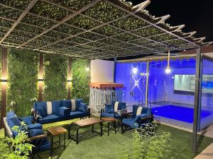 a patio with blue furniture and a pool at night at شاليه استكنان in Ash Shuqqah