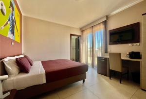 a hotel room with a bed and a desk and a television at Jogo Rooms in Matera