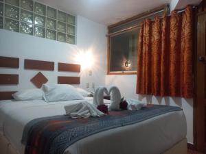 a bedroom with a bed with two swans on it at PAQARIQ INN HOTEL in Machu Picchu