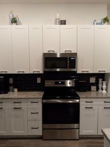 una cucina con armadietti bianchi, piano cottura e forno a microonde di Atlanta Cozy Loft Apartment ad Atlanta