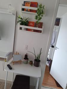 einen weißen Schreibtisch mit Topfpflanzen an der Wand in der Unterkunft Ponte Laguna, Pq Burle Marx, Apto 1 dorm e Varanda in São Paulo