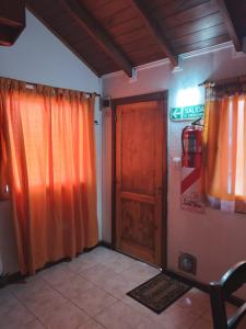 a room with a wooden door and orange curtains at Cabañas Monik in El Calafate