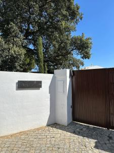 a white fence with a white door and a wooden gate at Bungalow Madeira - Casa das Lages - Almancil - Quinta do Lago in Almancil
