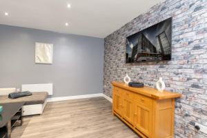 een kamer met een bakstenen muur en een tv bij SEASIDE SPACIOUS apartment in Peterlee