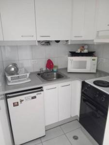 cocina con armarios blancos, fregadero y fogones en Apartamento Empresarial La Carolina zona comercial, en Quito