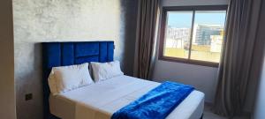 a bed with a blue headboard in a room with a window at La Rose Bleu 3 Chambre Terrasse in Tangier