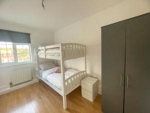 ein weißes Etagenbett in einem Zimmer mit einem Schrank in der Unterkunft Pinner apartments in Pinner