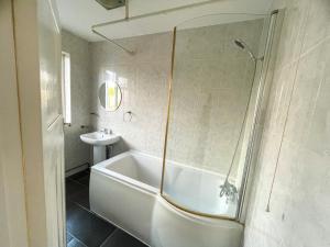 a white bathroom with a tub and a sink at Pinner apartments in Pinner