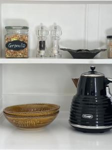 a black tea kettle and a bowl on a shelf at Matamata Historic Cottage- The Wash-House in Matamata