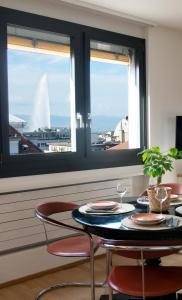 ein Esszimmer mit einem Tisch, 2 Stühlen und 2 Fenstern in der Unterkunft WowAppartements vue sur le jet d'eau in Genf