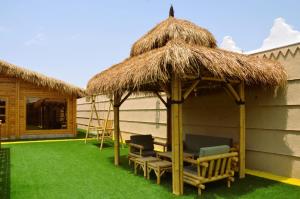 eine Hütte mit Stühlen und einem Grasdach in der Unterkunft شاليهات الأكواخ الثلاثة in Khalij Salman